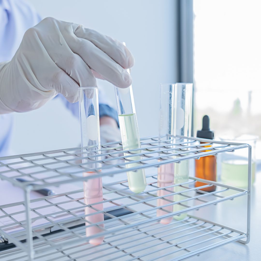 Person moving test tubes with substances in them.